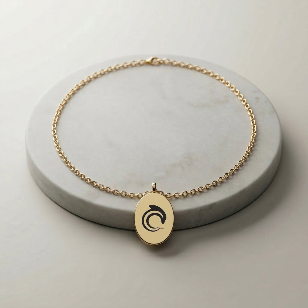 Gold necklace with a pendant on a gray surface with the AskDolphin logo