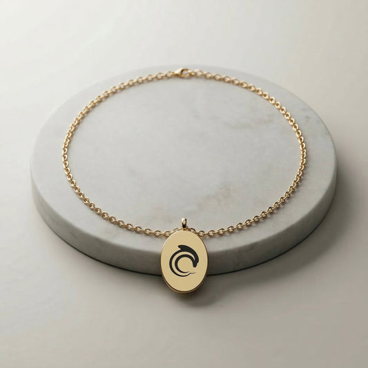 Gold necklace with a pendant on a gray surface with the AskDolphin logo